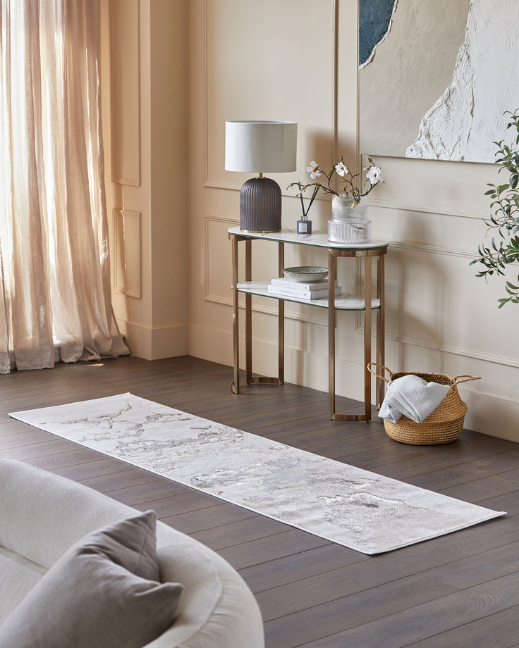 Elegant hallway with a marble-patterned runner, gold-framed console table, and soft furnishings for a stylish, inviting space.