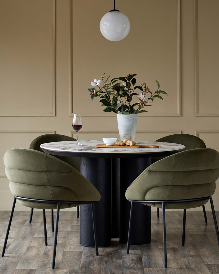 A modern round dining table with marble top and four stylish olive green velvet chairs. Contemporary dining room furniture.