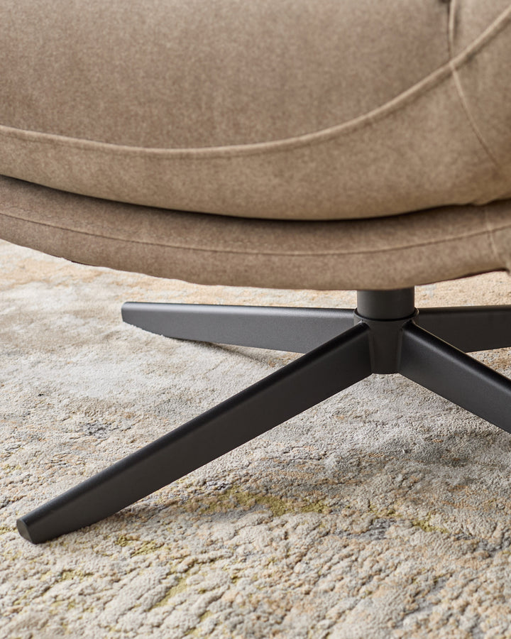Mocha fabric accent chair with black metal legs, close-up of splayed base on light carpet.