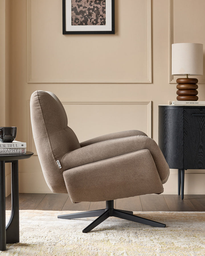 Mocha fabric accent chair with rounded back, black swivel base, shown in styled living room setting.