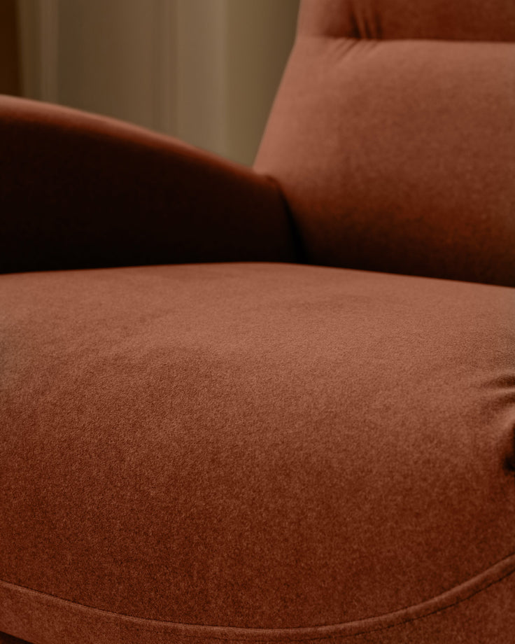 Piper accent chair in toffee red fabric, close-up detail showing seat cushion and curved armrest.