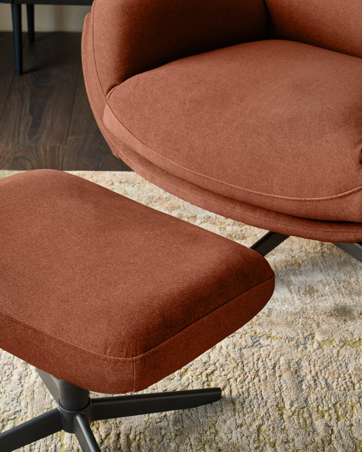 Piper accent chair and footstool in toffee red fabric with black metal base, positioned on a cream area rug.