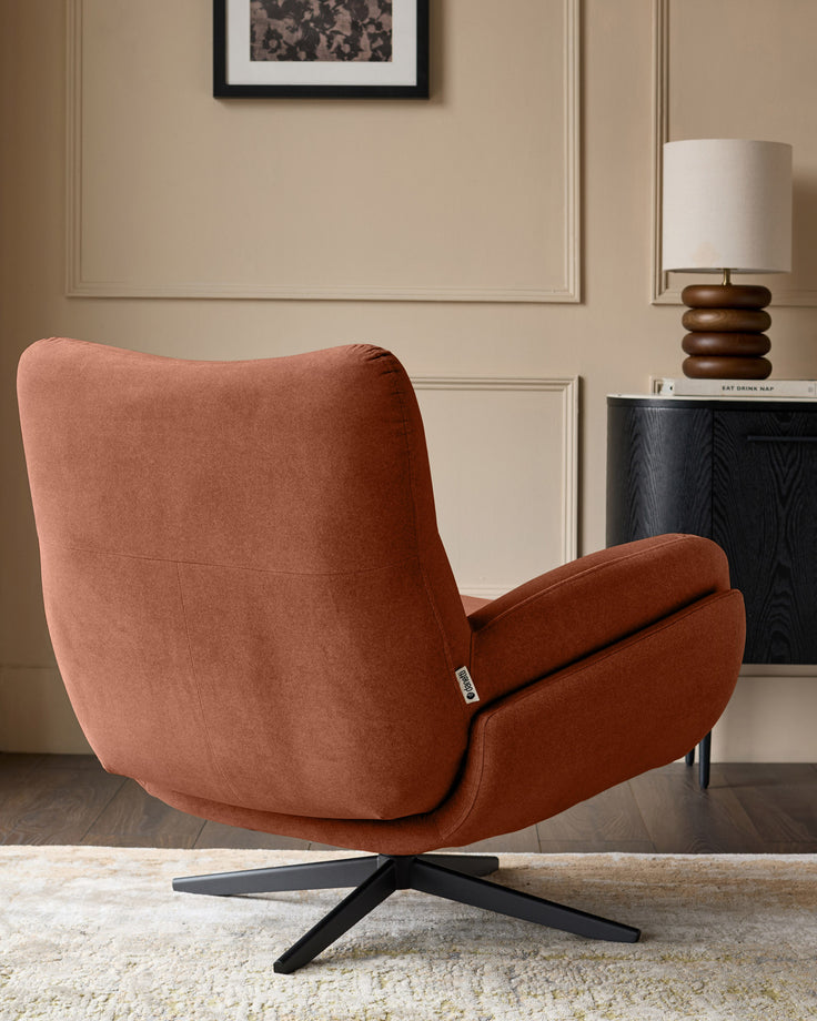 Toffee-red fabric accent chair with curved back, padded armrests, and black swivel base on neutral area rug.