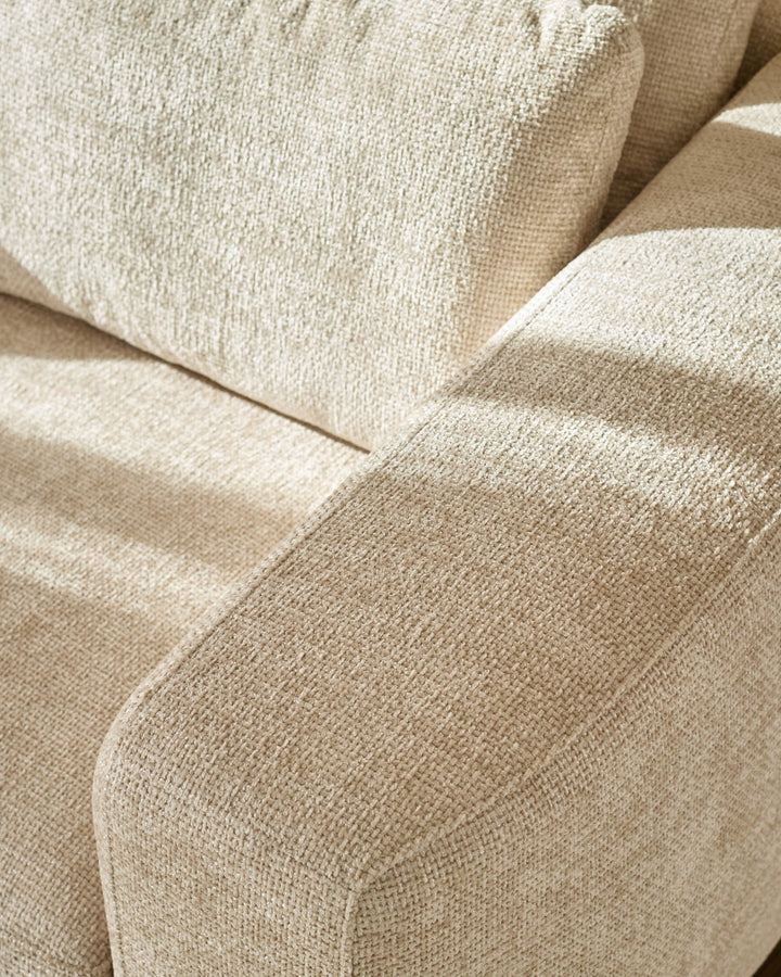 Close-up of natural beige fabric texture on Quinn 2-seater sofa, showing curved seam detail and woven upholstery.