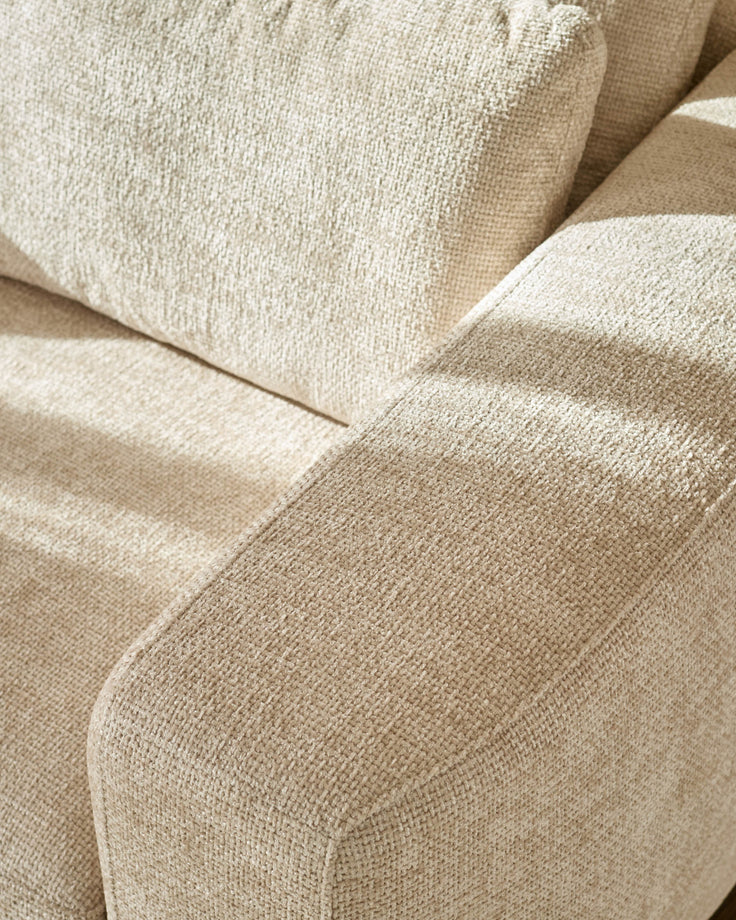Close-up of natural beige fabric texture on Quinn 2-seater sofa, showing curved seam detail and woven upholstery.