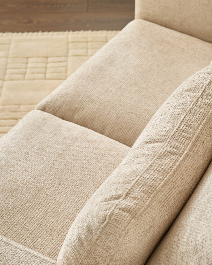 Quinn 2-seater sofa in natural fabric, close-up showing beige upholstery texture and quilted cushion detail.