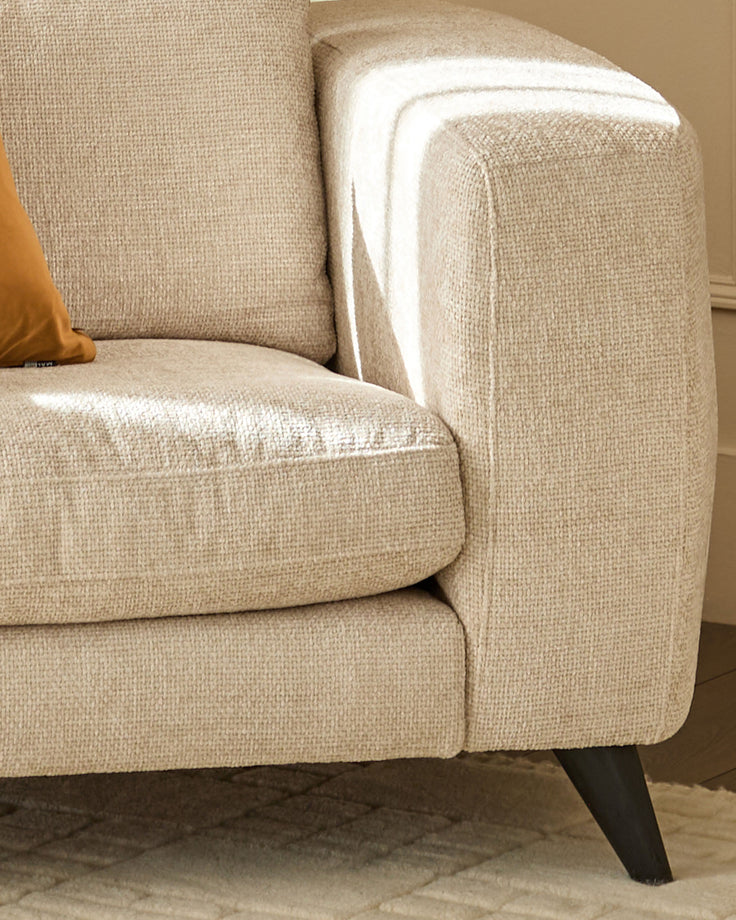Quinn armchair in natural fabric with rounded arms, tapered dark legs, and white piping detail on armrest.