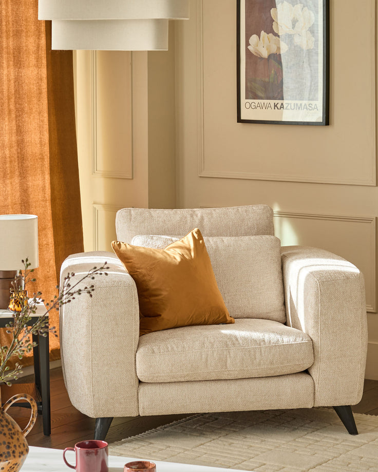 Quinn armchair in natural fabric with rounded arms, tapered legs, and gold accent pillow in styled room setting.