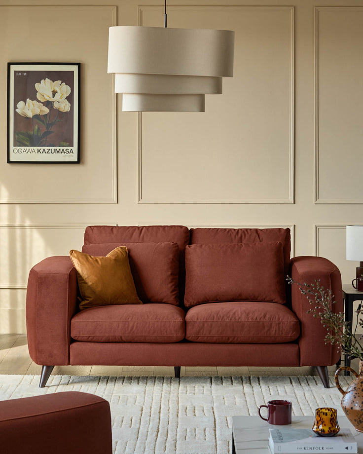 Quinn 2-seater sofa in toffee red fabric with wooden legs, styled in a neutral living room with pendant lamp and artwork.