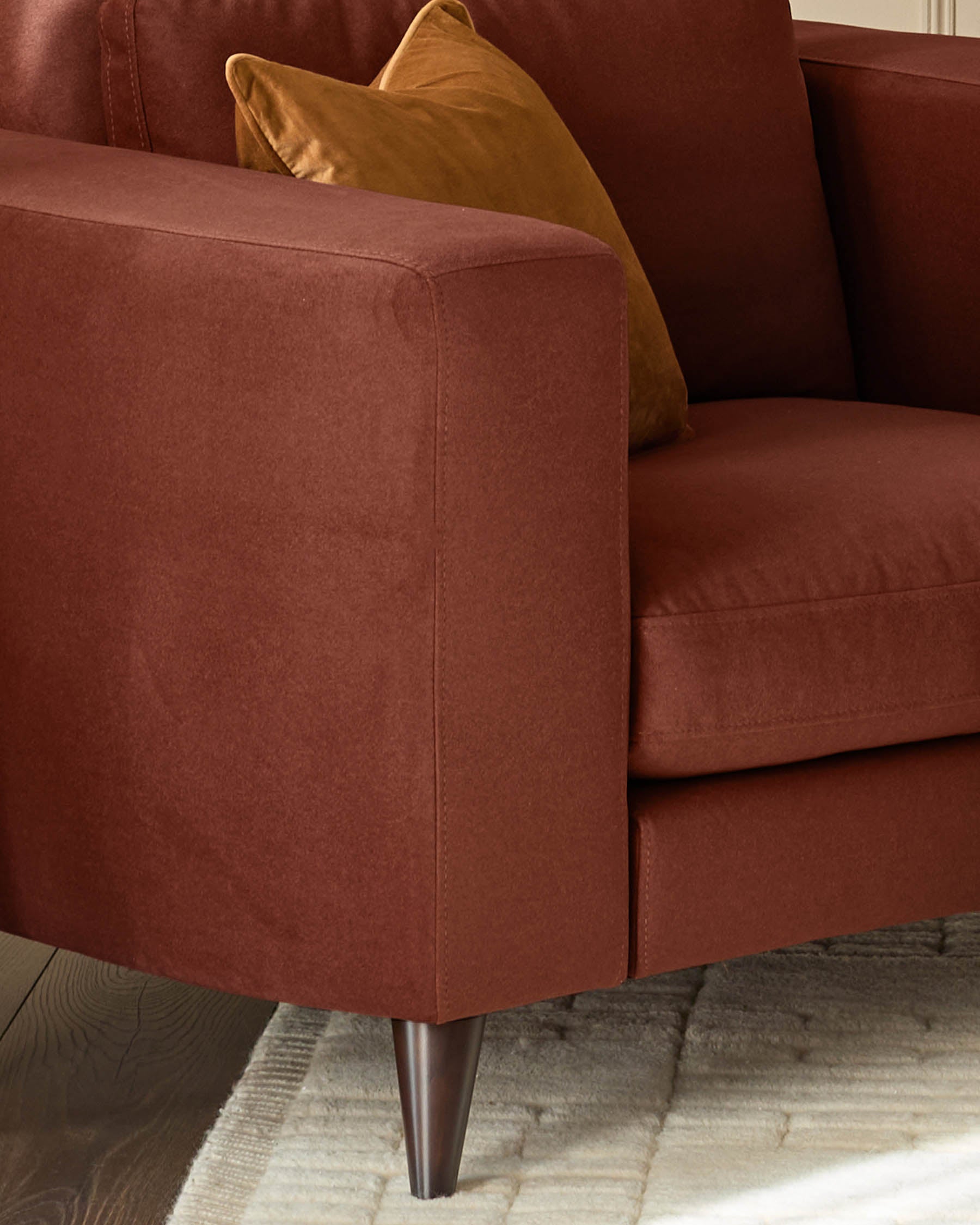Quinn armchair in toffee-red fabric with tapered metal legs, styled with a mustard-yellow accent pillow.