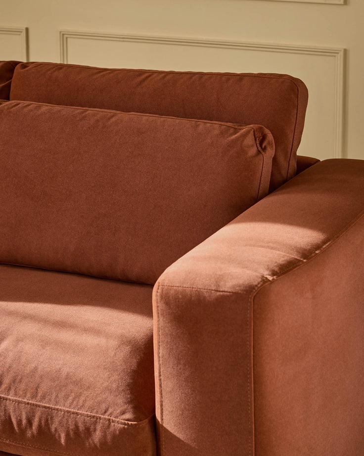 Quinn 2-seater sofa in toffee red fabric, showing curved armrest and cushioned seat from side angle.