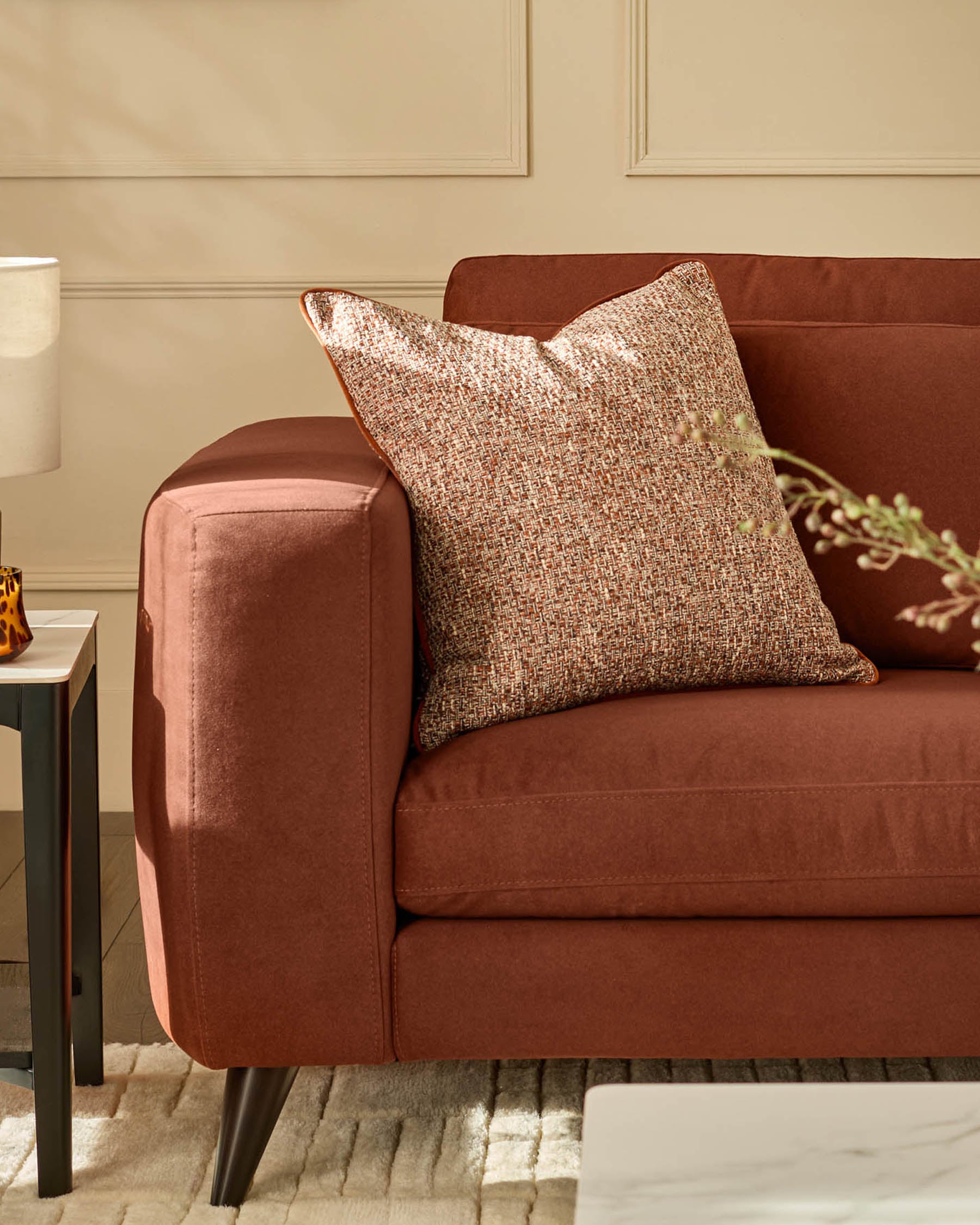 Quinn armchair in toffee red fabric with rounded arms, paired with a textured neutral pillow, shown at an angle.