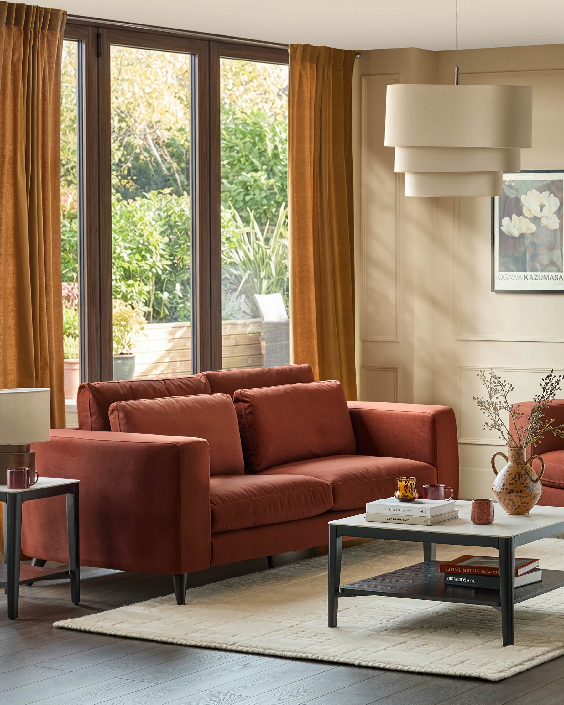 Quinn 3-seater sofa in toffee red fabric with dark legs, displayed in a bright living room setting.