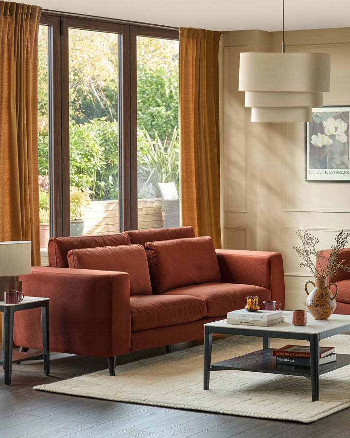 Quinn 3-seater sofa in toffee red fabric with dark legs, displayed in a bright living room setting.
