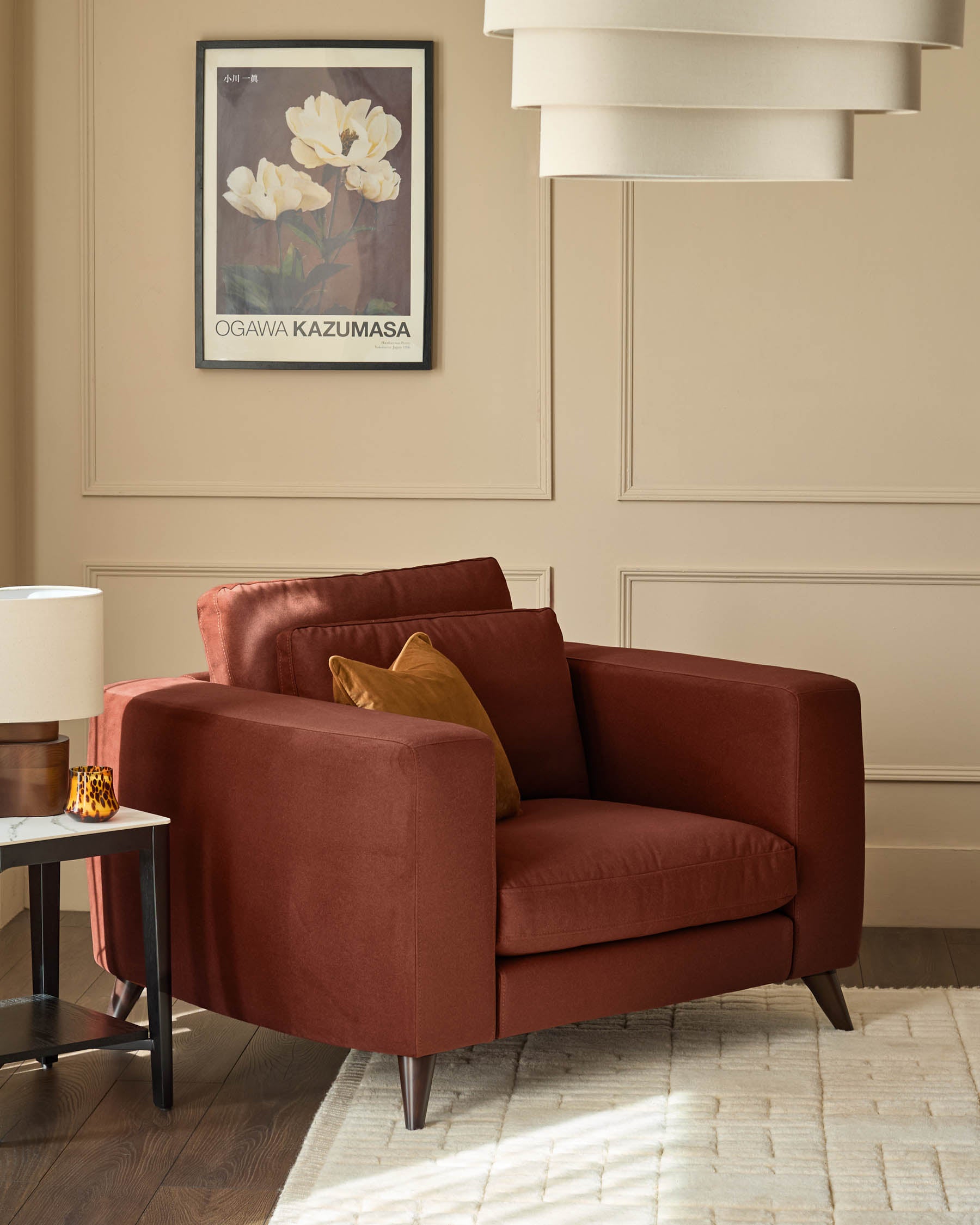 Quinn armchair in toffee red fabric, shown in a styled living room setting with decorative pillows and metal legs.