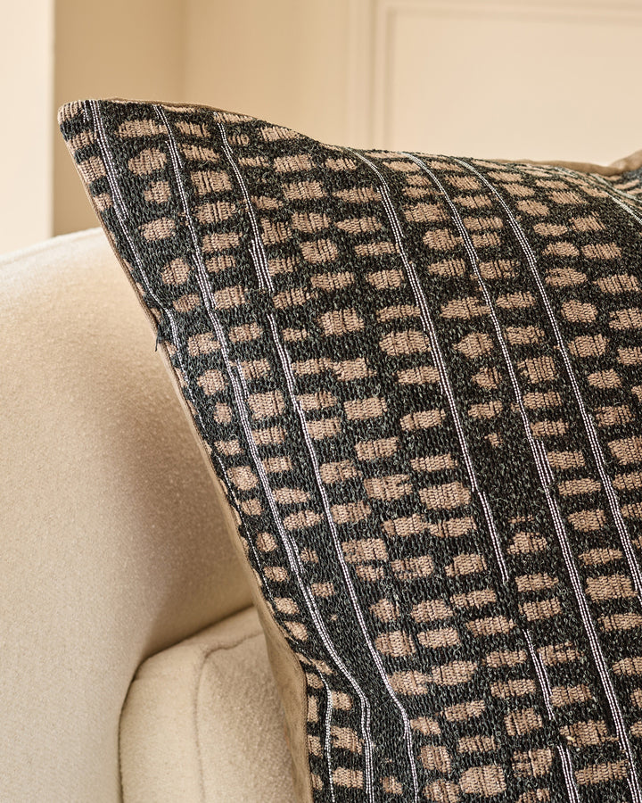 Rania cushion in black with beige checkered pattern, displayed on a cream armchair at an angle.