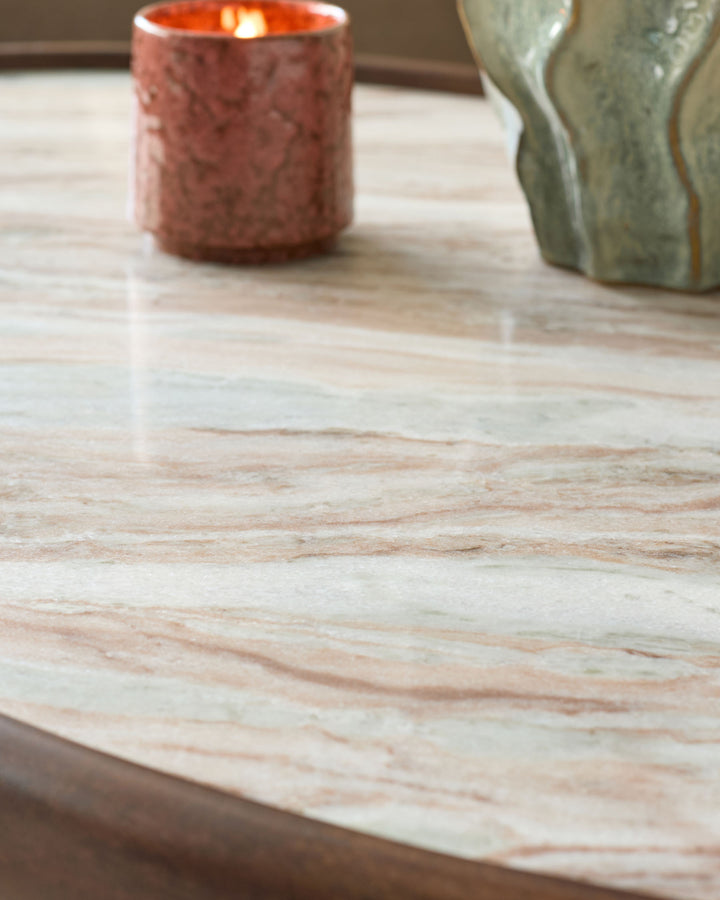 Rayna coffee table with light marble top and dark wood base, styled with a coral candle and green vase.