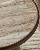 Rayna side table in dark wood with travertine marble top, showing curved edge detail and natural stone grain pattern.