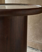 Dark wood round side table with marble top, cylindrical pedestal base, angled view showing wooden grain detail.