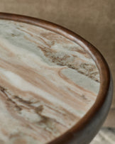 Rayna side table with dark wood frame and marble top, close-up angled view showing wood grain detail.