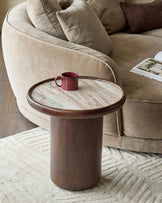 Rayna side table in dark wood with round Toronto marble top, cylindrical pedestal base, styled with burgundy mug in living room setting.