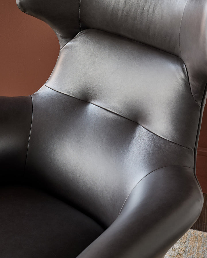 Black leather occasional chair with curved armrests and padded seat, shown from angled side view.