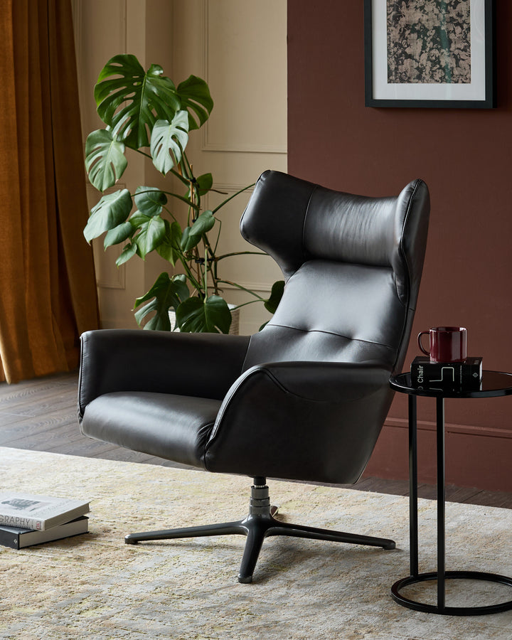 Black leather occasional chair with high back, padded armrests, and swivel base, styled in modern living room setting.