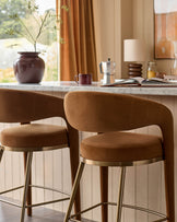 Two plush bar stools with brown upholstery and sleek metal legs are positioned at a kitchen counter.
