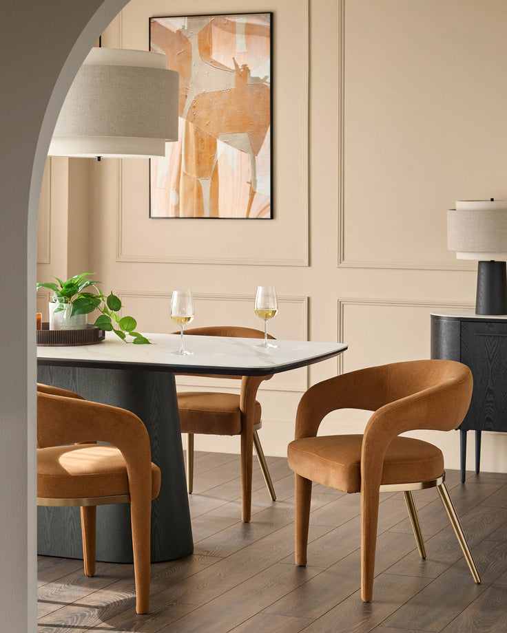 Contemporary dining space with ochre chairs, a marble-topped table and statement artwork, creating a stylish, inviting ambience.