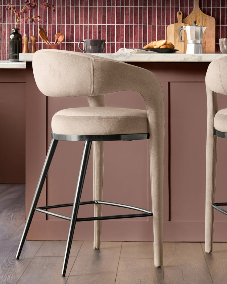 Champagne velvet bar stool with curved backrest, metal footrest, and tapered wooden legs at a kitchen island.