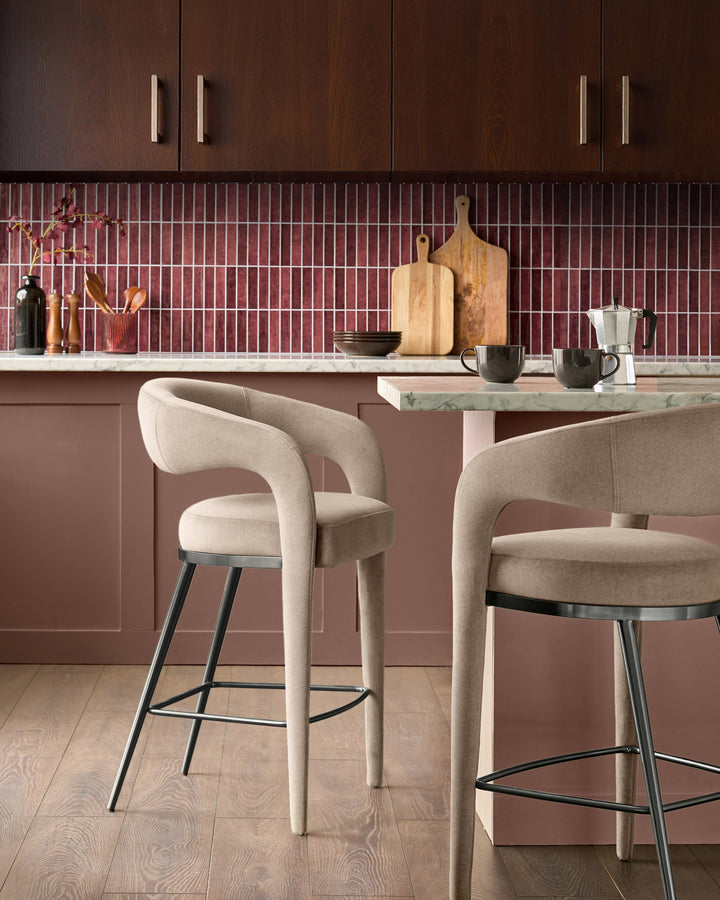 Rhett bar stool in champagne velvet with curved backrest and black metal legs, shown in kitchen setting.