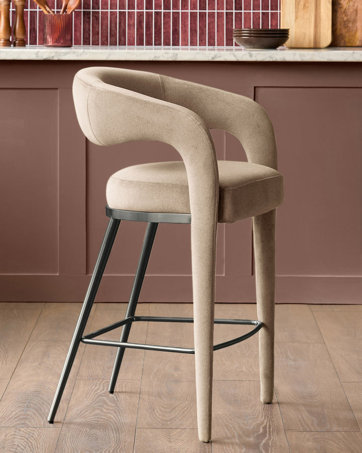 Champagne velvet bar stool with curved backrest, black metal legs and footrest, shown in kitchen setting.