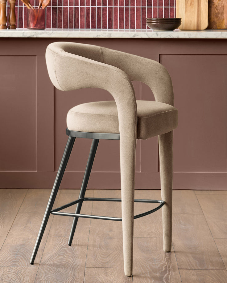 Champagne velvet bar stool with curved backrest, black metal legs and footrest, shown in kitchen setting.