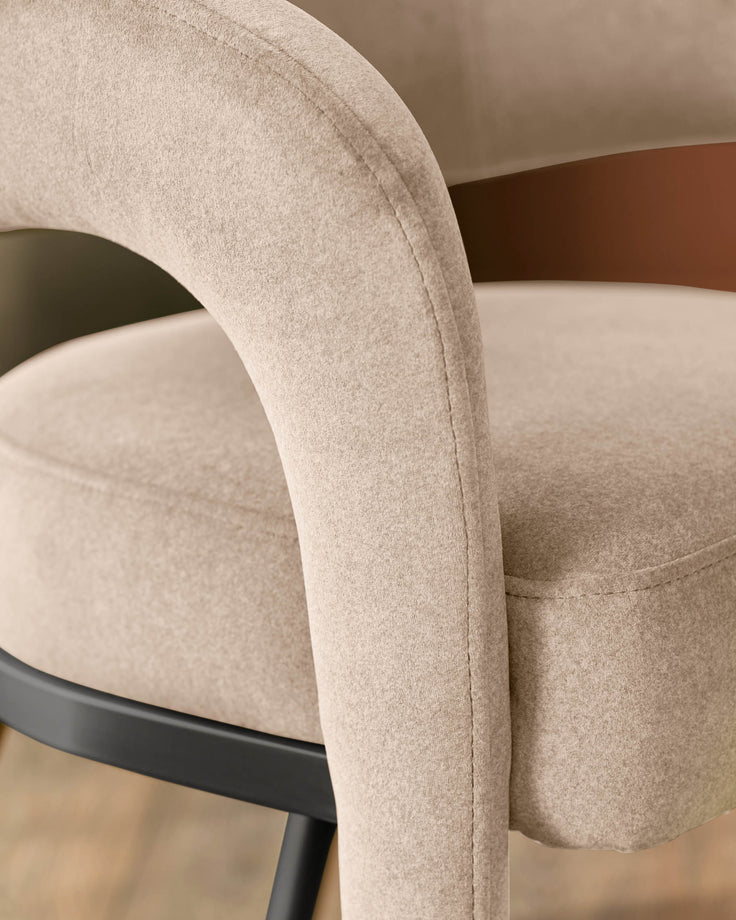 Rhett dining chair in champagne velvet, showing curved armrest and seat detail from side angle.