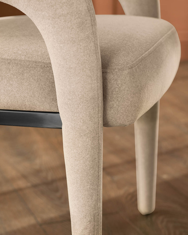 Rhett dining chair in champagne velvet, showing curved backrest and cylindrical leg from side angle.
