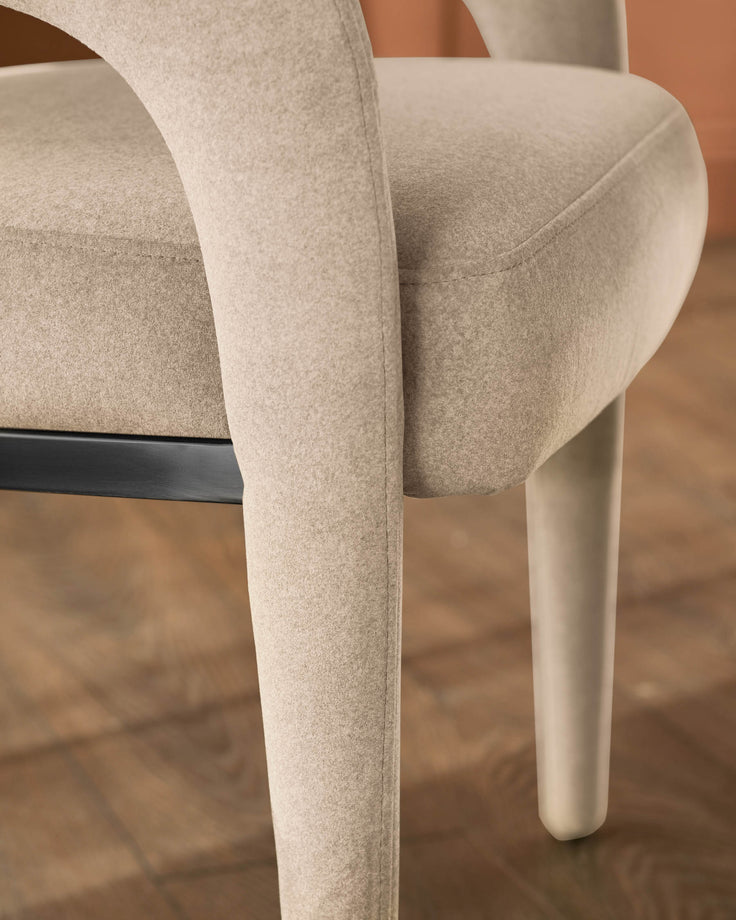 Rhett dining chair in champagne velvet, showing curved backrest and cylindrical leg from side angle.