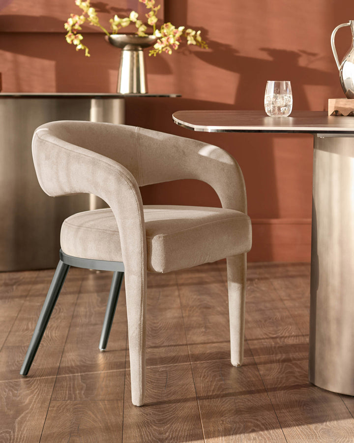 Champagne velvet dining chair with curved back, metal legs, positioned at wooden table in modern interior setting.