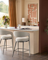 Two stylish bar stools with curved backrests and dark metal legs sit at a kitchen island.