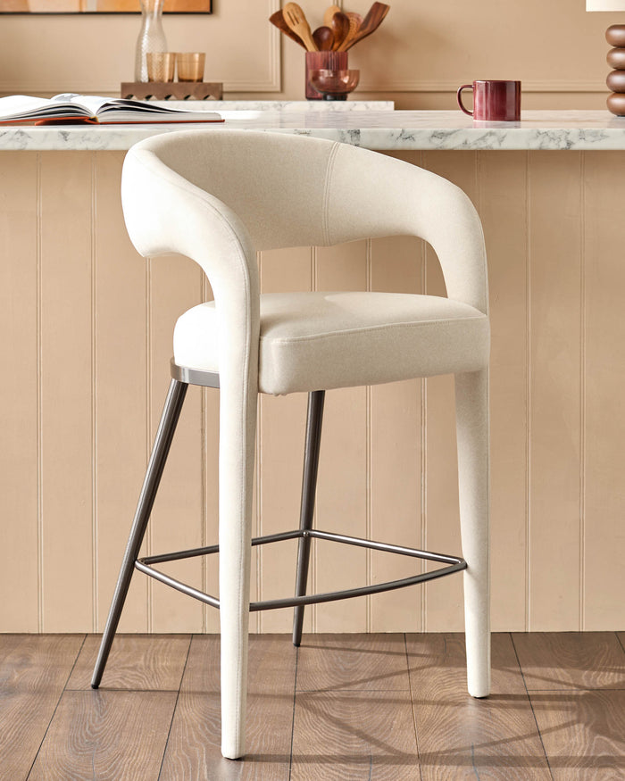 A stylish, modern bar stool with a cream fabric seat and backrest, atop a sturdy, dark metal frame.