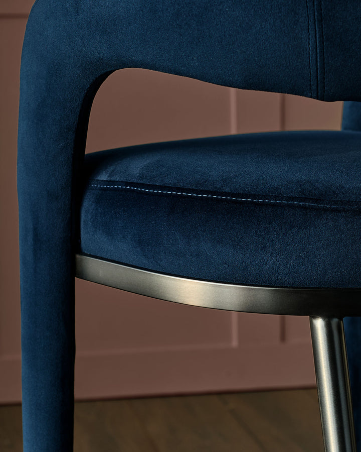 Rhett bar stool in dark navy velvet with wooden backrest and metal footrest detail, side view.