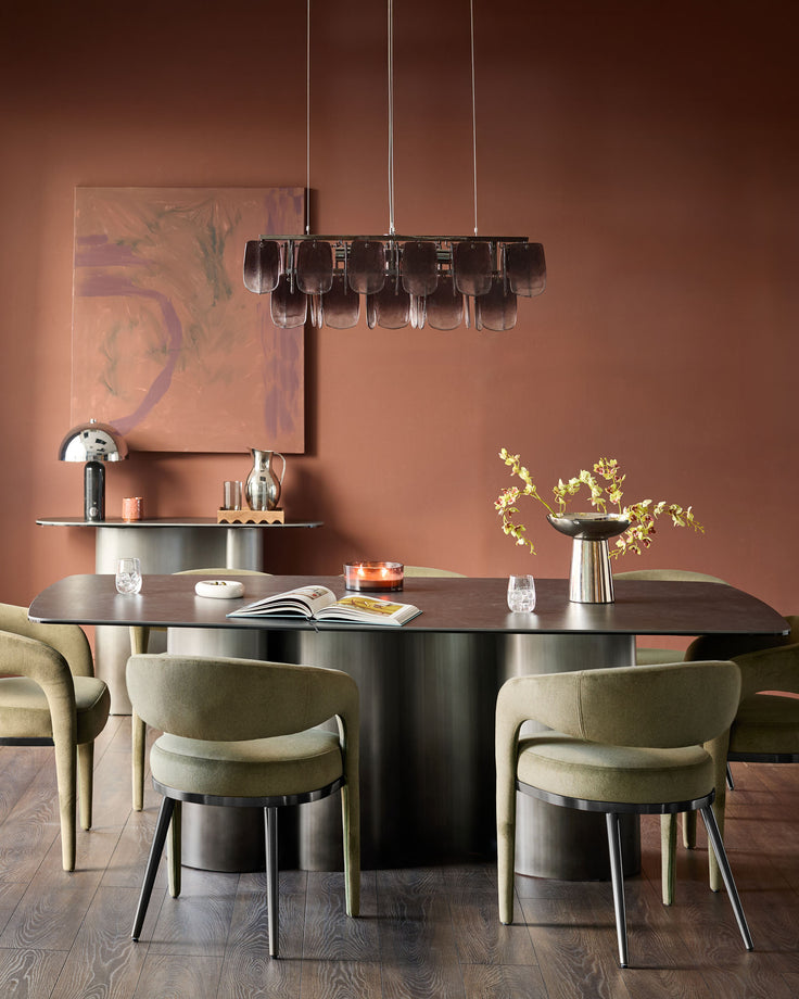 Rhett dining chair in olive-green fabric with curved back and metal legs, shown at modern dining table.