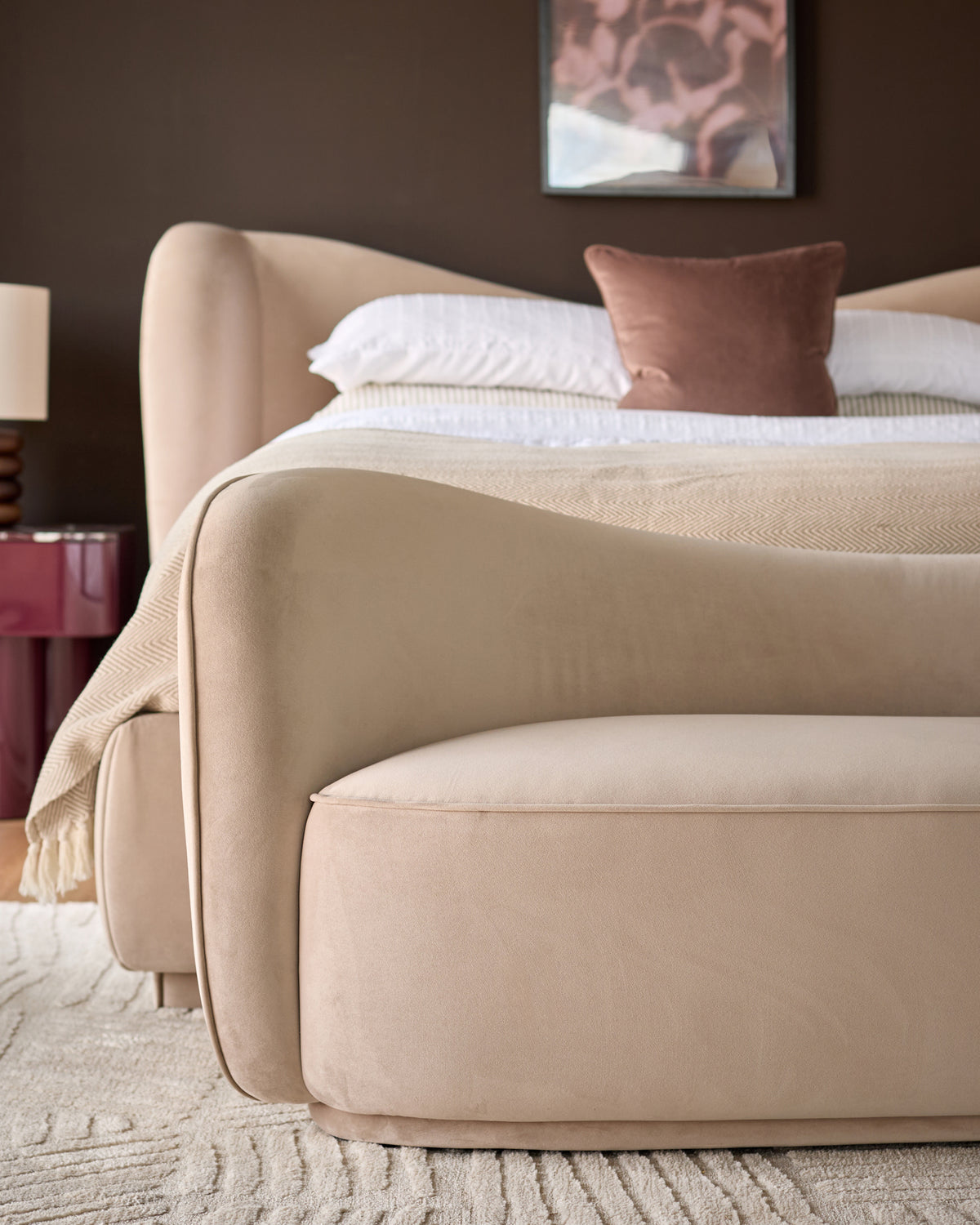 Champagne velvet accent sofa with curved arms and rounded silhouette, displayed in bedroom setting.