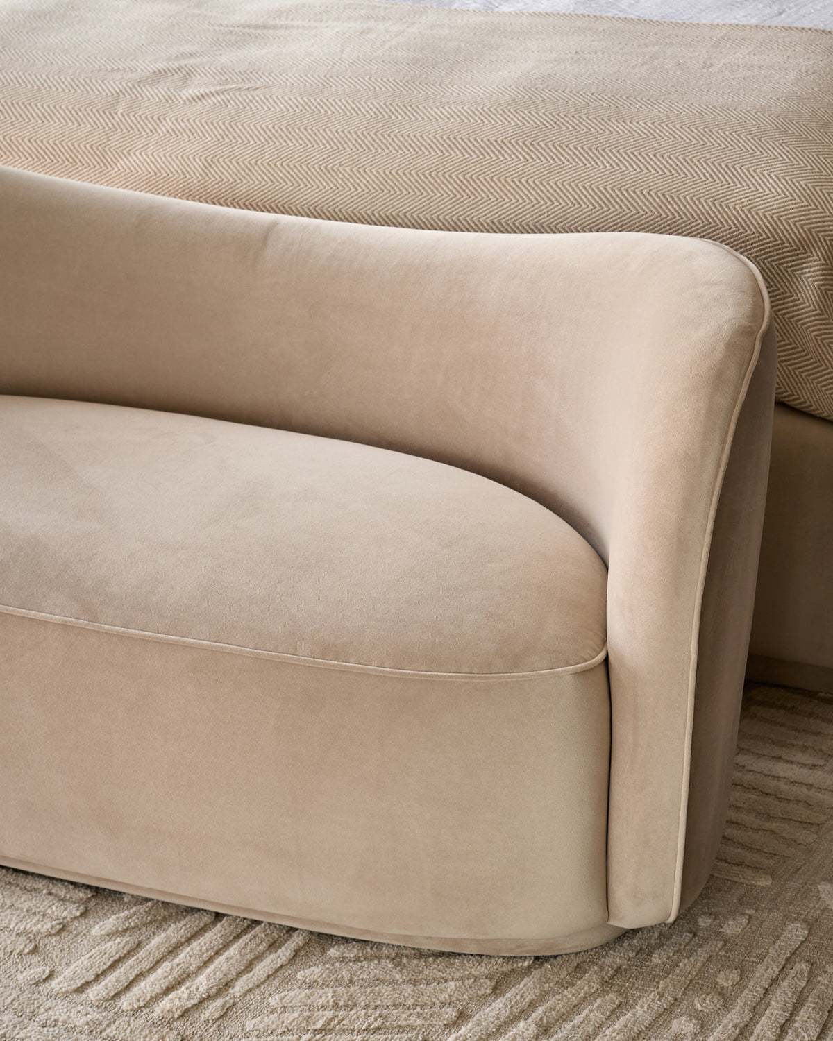 Rhiannon Accent Sofa in champagne velvet, showing curved armrest and seat detail from side angle on neutral patterned rug.