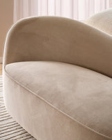 Champagne velvet accent sofa with curved, rounded back and seat, shown at an angle in a bright room with sheer curtains.