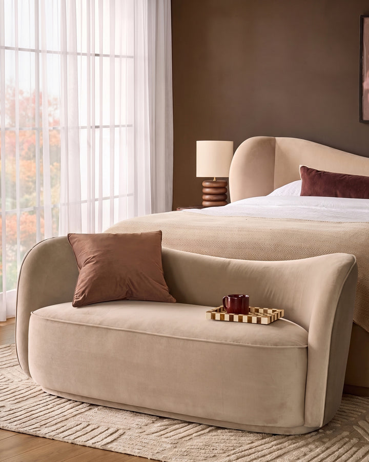 Champagne velvet Rhiannon accent sofa with curved arms and back, displayed in a bedroom setting with decorative pillow and tray.