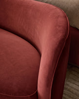 Rhiannon accent sofa in toffee red velvet, close-up of curved armrest and piping detail against patterned rug.