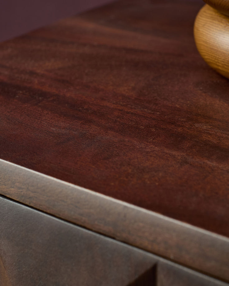 Dark mango wood bedside table with natural grain texture and light wood edge detail, angled view.