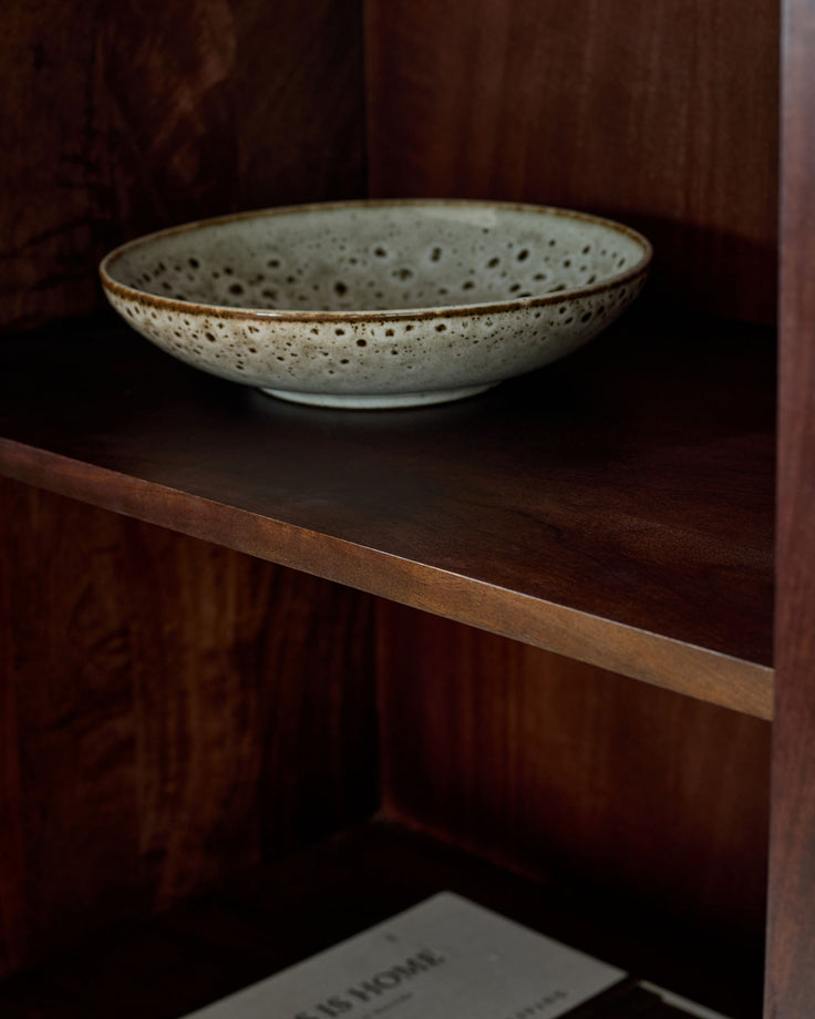Dark mango wood sideboard with open shelf displaying a speckled ceramic bowl.