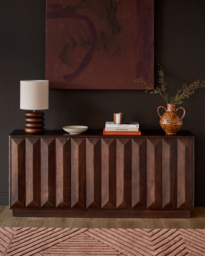 Dark mango wood sideboard with vertical fluted panel detailing on the front facade, displayed in a styled interior setting.