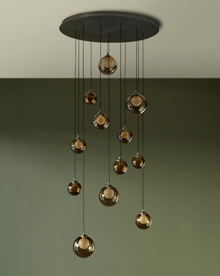A stylish pendant light with cascading smoked glass globes, suspended from a circular ceiling plate. Adds modern elegance to any space.
